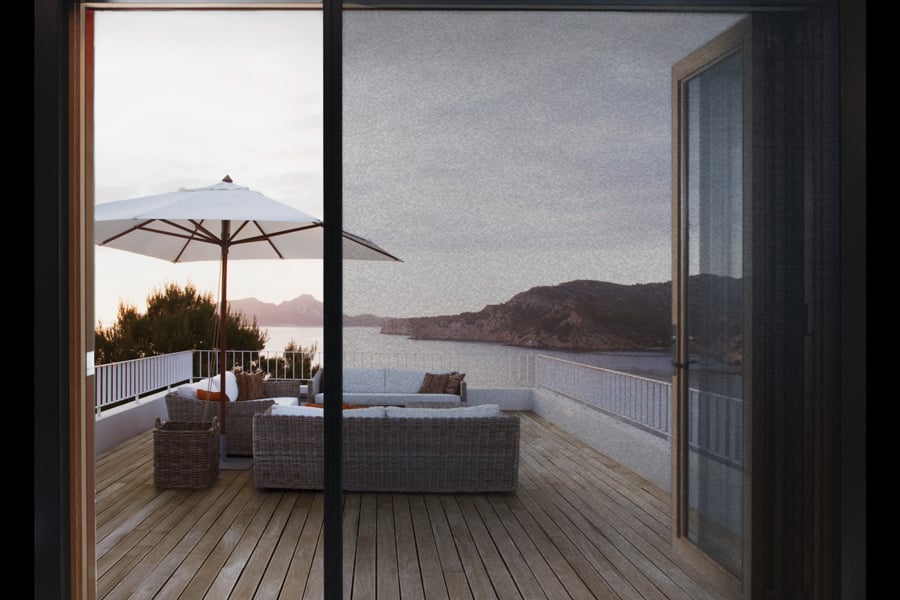 An open Andersen big door with retractable screen facing a deck and oceanside views