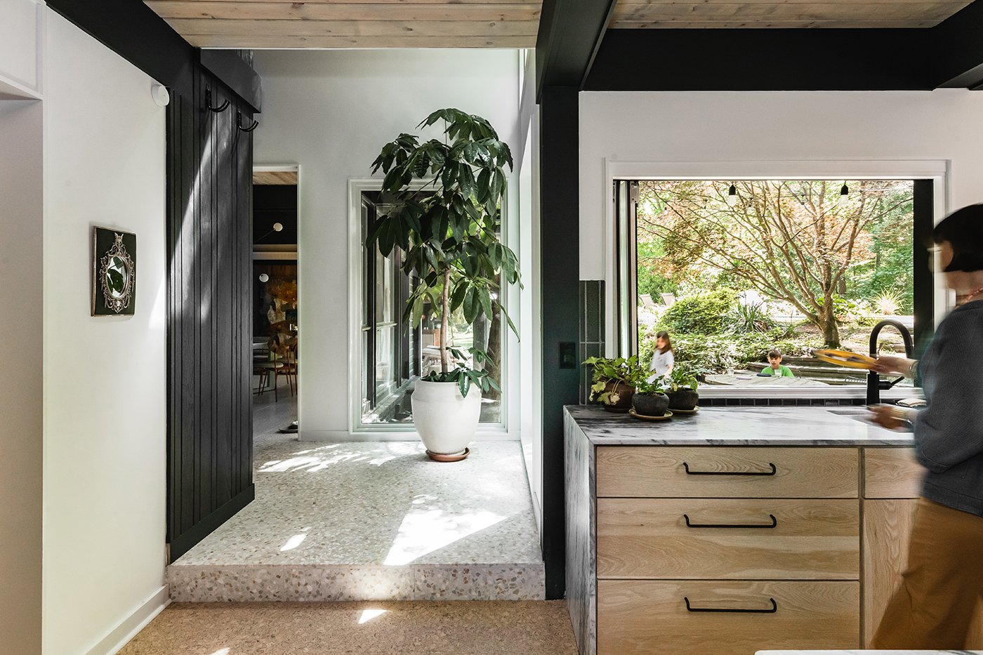 A woman hands a plate out an Andersen Folding Pass-Through Window.