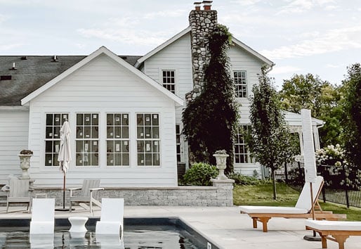 Liz Marie Galvan’s farmhouse viewed from the back where a new addition featuring a primary suite with sunroom faces the swimming pool  