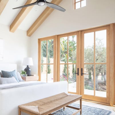 An airy bedroom with high ceilings and a four-panel E-Series Hinged Patio Door.