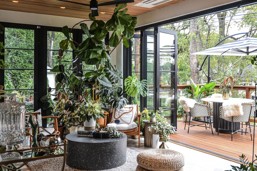 An open Folding Outswing door connects the plant-filled sunroom with the adjoining deck creating an indoor/outdoor space