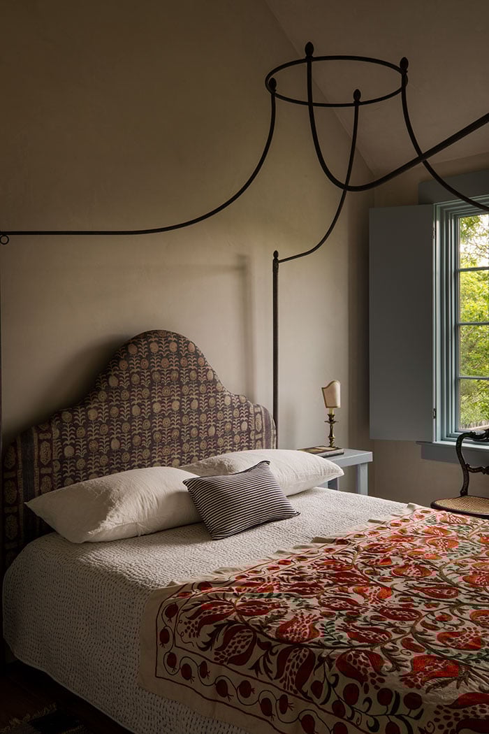 On the left, an image of a bedroom with a canopy bed and an A-Series Casement Window painted blue to match the shutters and trim around it. On the right, an image of a moody bathroom with a tub under a white A-Series Casement Window with colonial grilles.