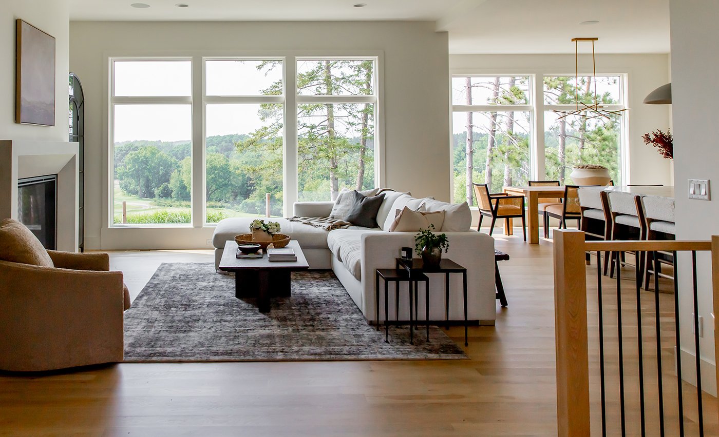 An open concept living area with two walls of Andersen® 400 Series Casement Windows joined to transom windows above.