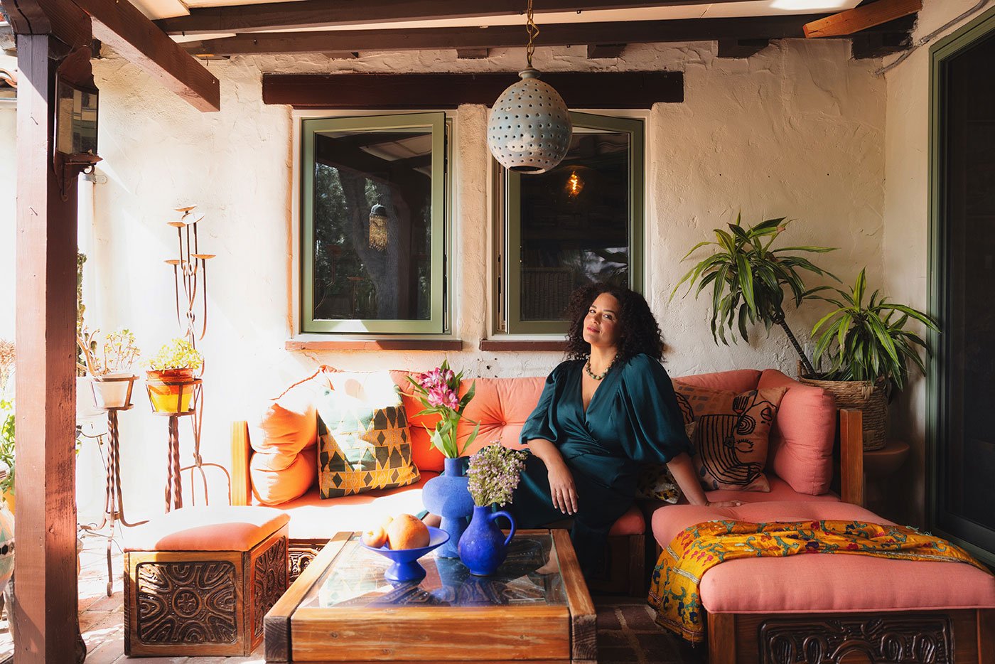 Justina Blakeney sits on an outdoor sofa underneath a set of two E-Series Casement Windows.