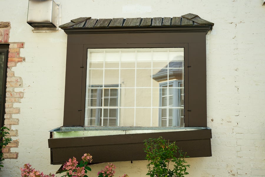 An old picture window with a storm window and a sagging window box.