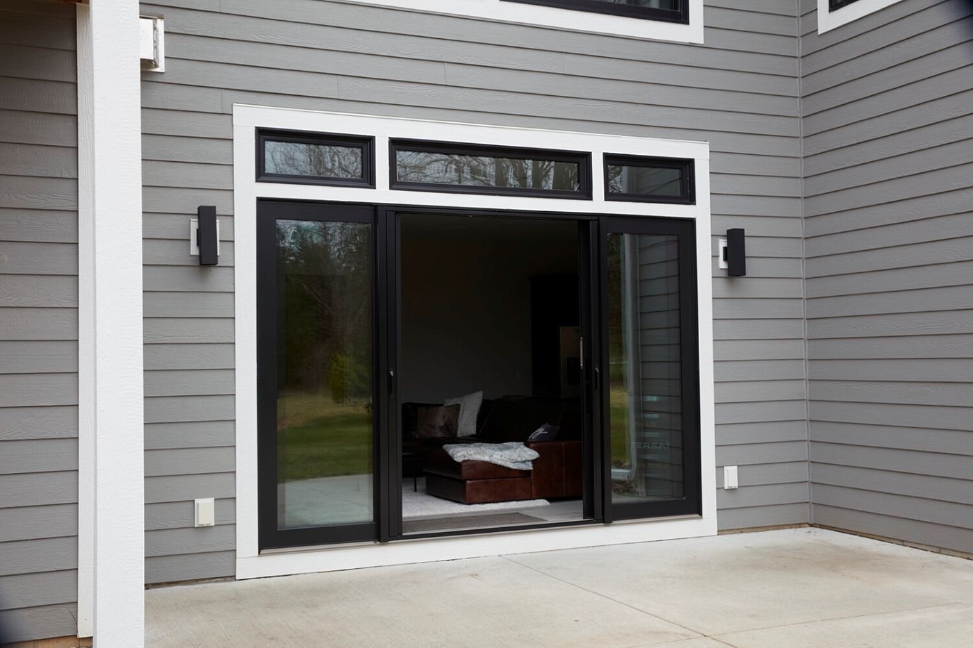 An open four panel gliding patio door with black frames and transoms.