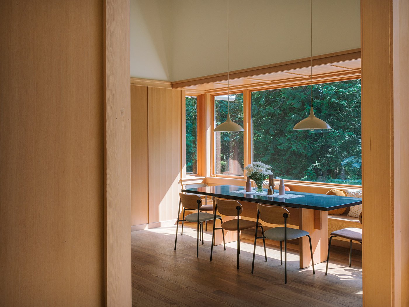 A dining space set inside a nook with windows on three sides that effectively creates an oversized bay window.